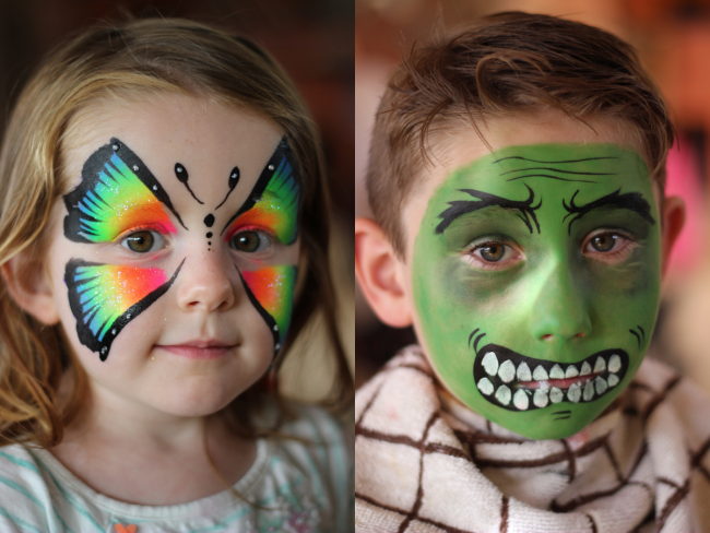 A young girl with a rainbow butterfly face paint and a young boy with The Hulk face paint.